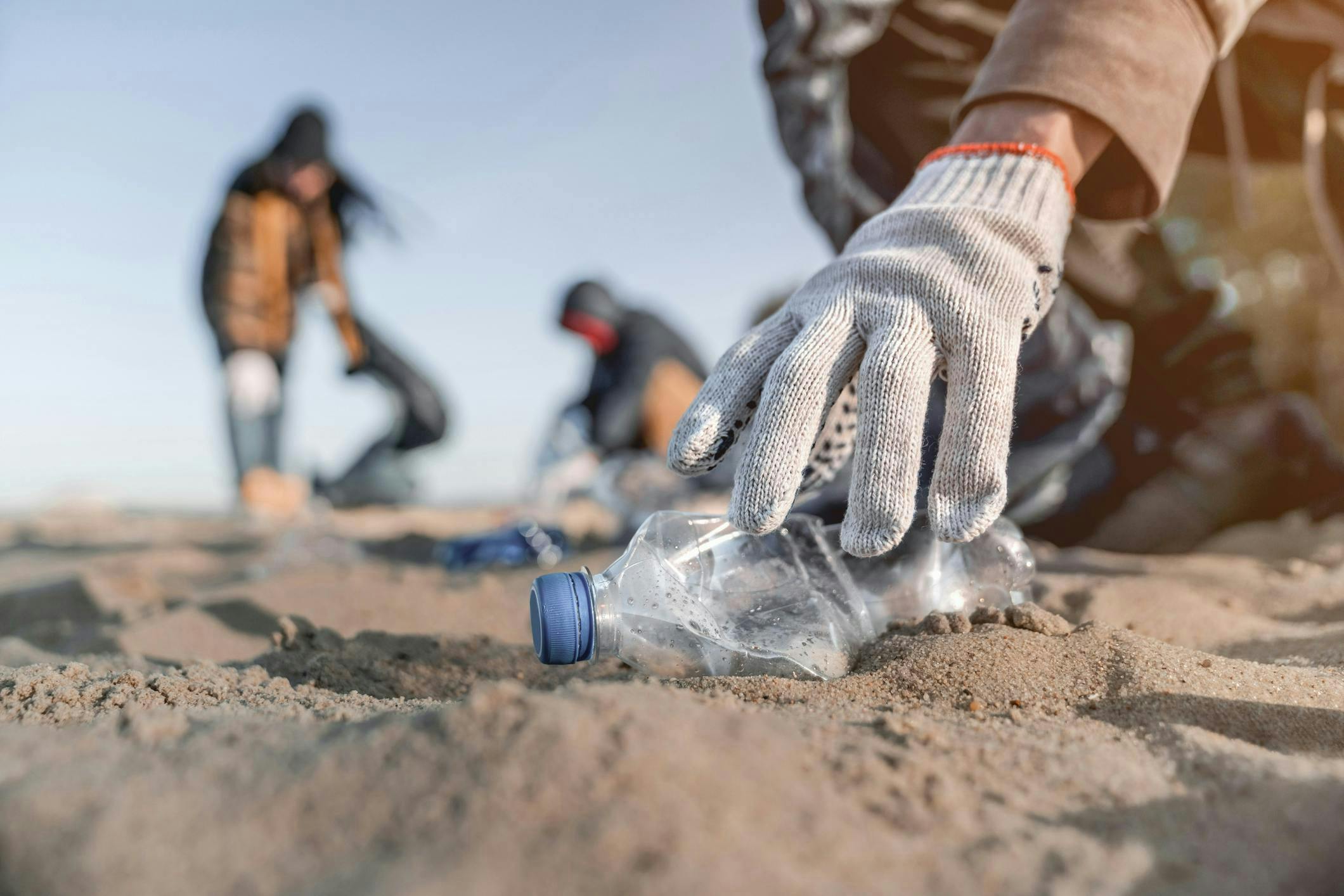 Hand removing plastic bottle from the beach